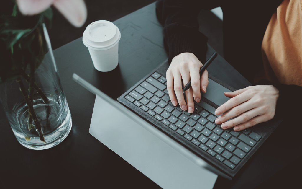 two hands typing on the laptop on the black table