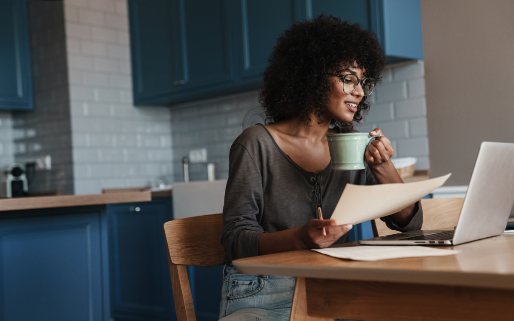 a woman looking at the monitor with the paper and cup on her hands