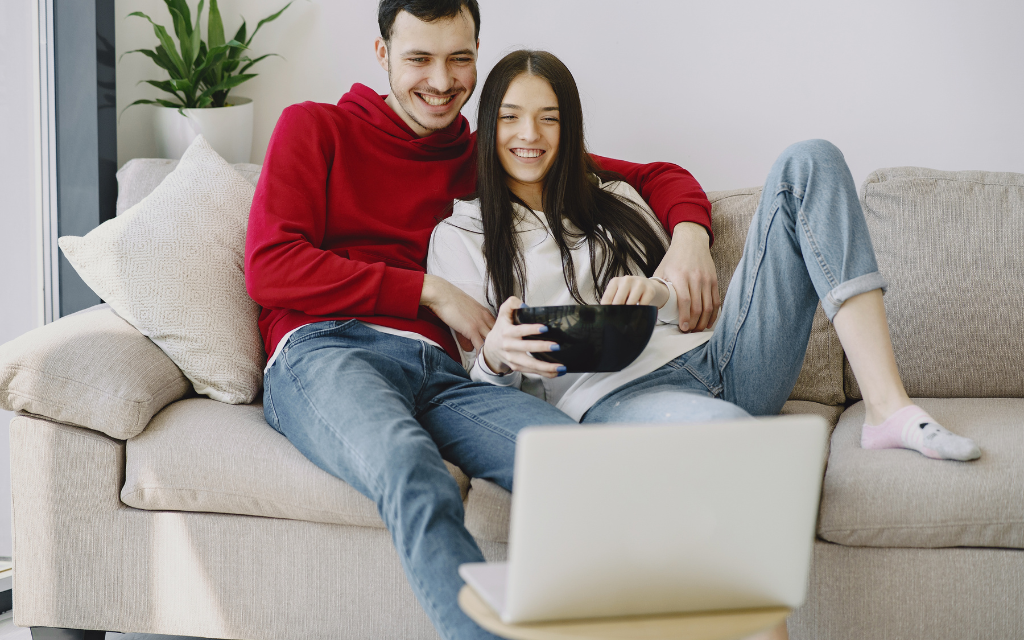 a woman and a man watching a laptop on the sofa