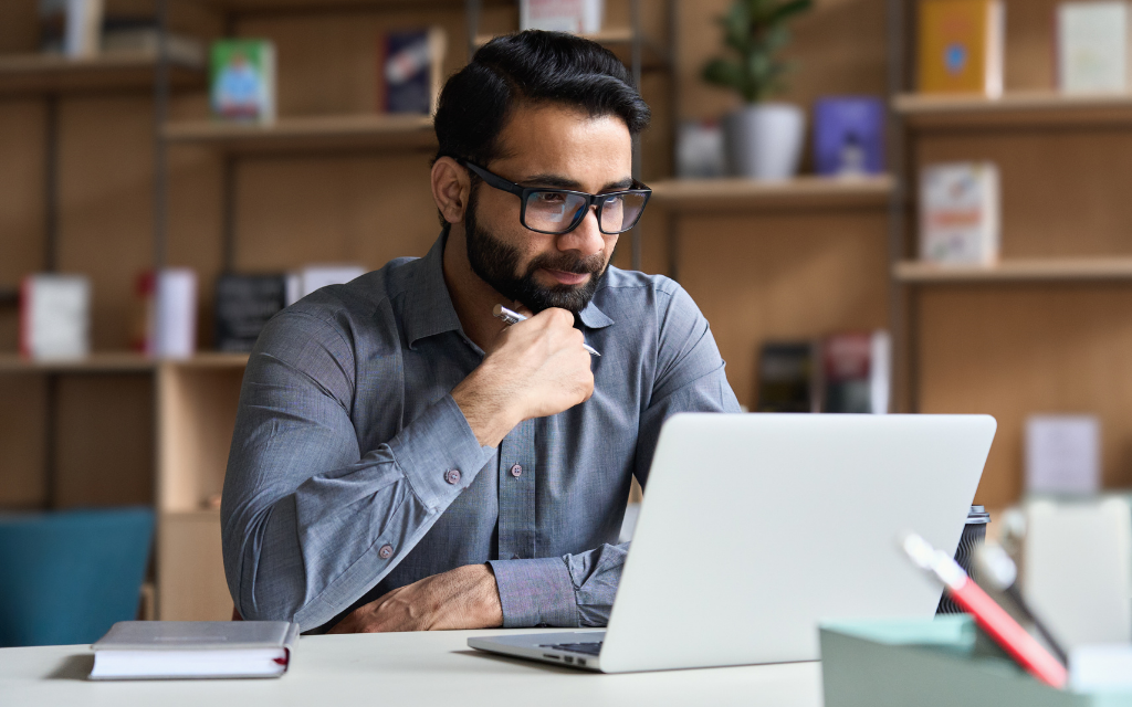 a man watching his laptop with glasses on