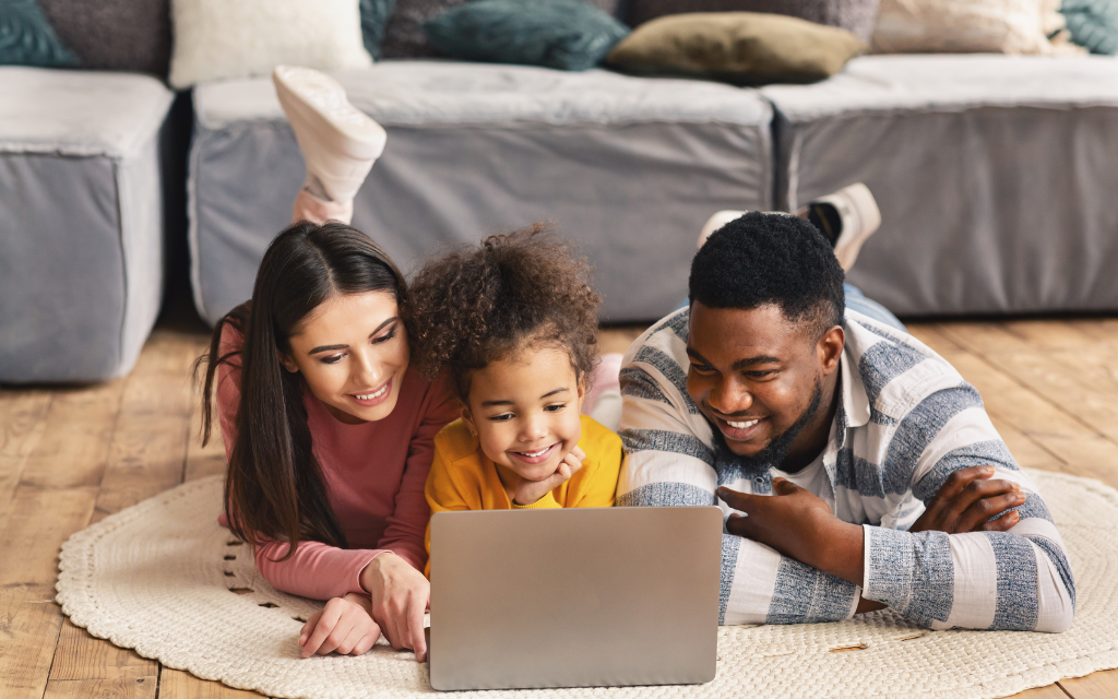 a woman, a man, a child watching laptop together