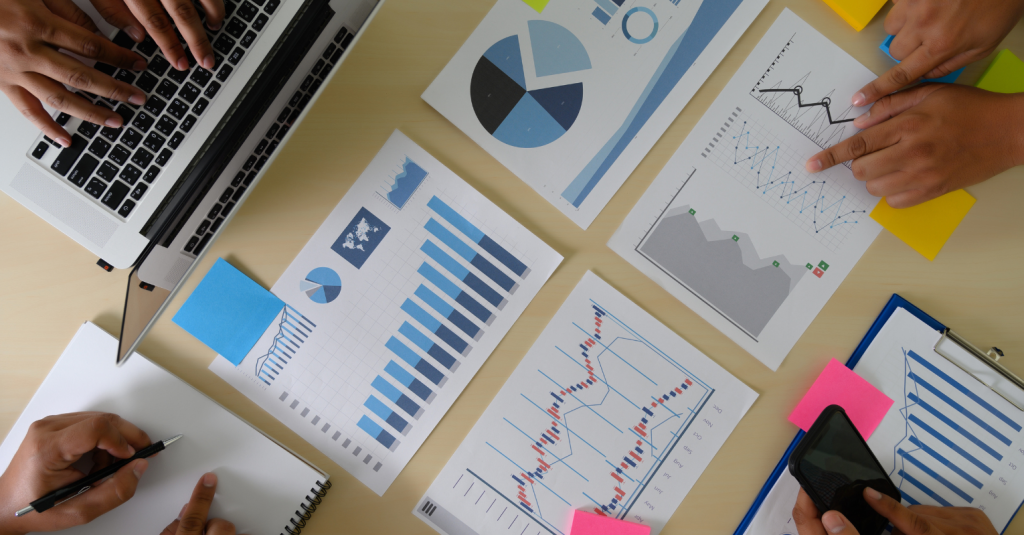 Overhead view of a team analyzing charts and graphs on a desk.