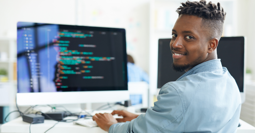 Smiling developer working on code at a computer.